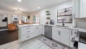A modern kitchen with white cabinetry, a central island, a dishwasher, and a built-in oven. - 3/2 Beautiful Pool Home + Garage + Pet Friendly (Lakeland)