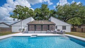 A modern house with a swimming pool, a covered patio, and a fenced backyard. - 3/2 Beautiful Pool Home + Garage + Pet Friendly (Lakeland)