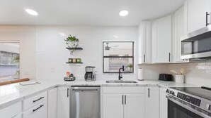 A modern kitchen with white cabinets, stainless steel appliances, and a window above the sink. - 3/2 Beautiful Pool Home + Garage + Pet Friendly (Lakeland)