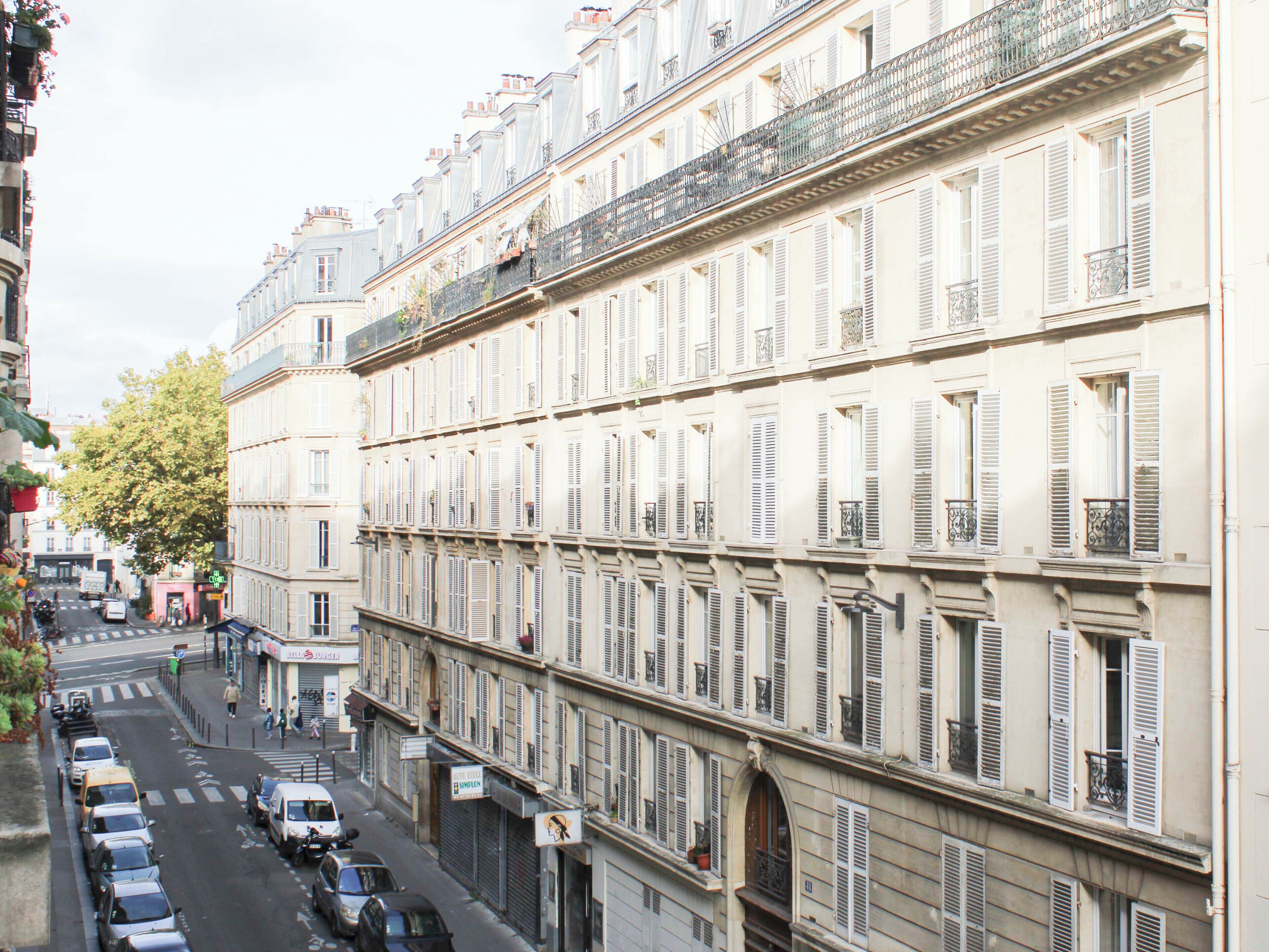 A row of multi-story buildings with uniform architectural style, featuring balconies with metal railings and shutters.