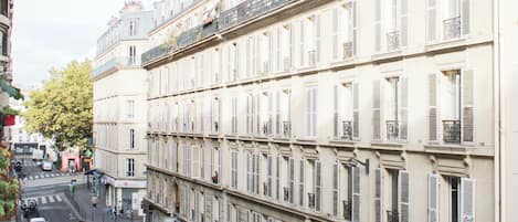 A row of multi-story buildings with uniform architectural style, featuring balconies with metal railings and shutters.