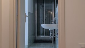 A hallway leading to a bathroom with a glass shower enclosure and a white sink. - The House of Archibugi (Sulmona)
