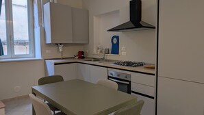 A compact kitchen with a gas stove, sink, and a clock on the wall. - The House of Archibugi (Sulmona)