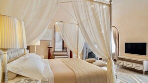 Une chambre à coucher avec un lit à baldaquin, une télévision, un bureau et une chaise.