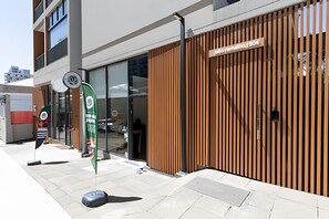 A modern building with a wooden facade, a sign reading 'Jumbo Mining,' and a green flag with a logo. - Apê Perdizes C/AR piscina prox Allianz (São Paulo)