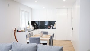 A modern kitchen with white cabinets, a black backsplash, and a dining area with a table and chairs. - 3 bedroom apartment near the center of Ponte de Lima with private parking (Ponte de Lima)