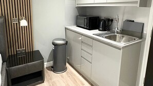 Cocina compacta con microondas, cafetera y lavabo.