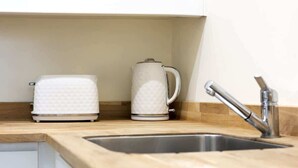 Una cocina con encimera de madera, un lavamanos de acero inoxidable y dos electrodomésticos blancos.