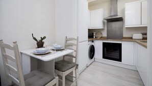 Una cocina compacta con lavadora, horno y comedor con sillas y mesa.
