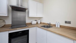 Una cocina moderna con electrodomésticos de acero inoxidable, armarios blancos y encimera de madera.