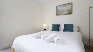 Una habitación de hotel con una cama bien hecha, una lámpara de noche y un cuadro en la pared.