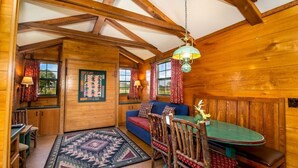 A cozy cabin interior with a wooden dining table, blue sofa, and rustic decor.