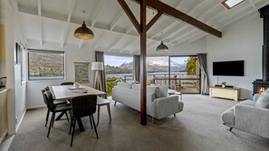 A spacious living area with a dining table, sofas, and a fireplace. - Perfect on Perkins - Lake views (Queenstown)