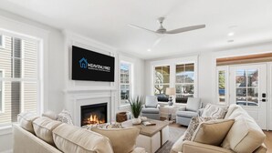 Ein geräumiges Wohnzimmer mit Kamin, bequemen Sitzmöglichkeiten und einem an der Wand befestigten Fernseher.