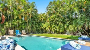 Une piscine dotée de chaises longues et entourée d’un jardin tropical.