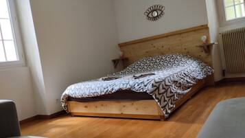 Une chambre à coucher avec un lit en bois, une couvre-lit à motifs, un élément décoratif mural et un radiateur.
