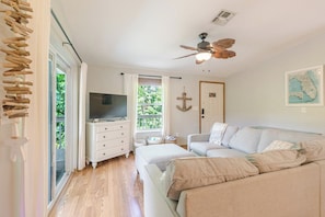 Ein Zimmer mit Fernseher auf einer Kommode, Deckenventilator, einer Couch und einer Karte an der Wand.