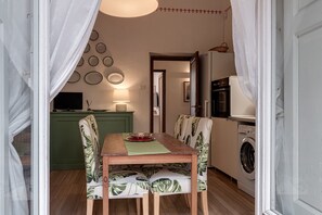 A dining area with a table, chairs, a washing machine, and a kitchen in the background. - Florence Apartment with Patio in the City Center (Firenze)