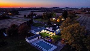 Eine Vogelperspektive eines Wohngebiets mit einem großen Haus, das einen Swimmingpool, einen gepflegten Rasen und eine Auffahrt zum Haus zeigt.