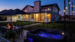 Ein Haus mit überdachter Terrasse, Whirlpool und Lichterketten.