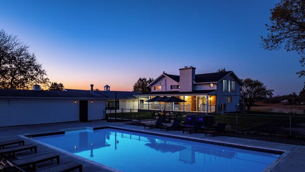 Ein modernes Haus mit Swimmingpool, Sitzgelegenheiten im Freien und einer gut beleuchteten Terrasse.