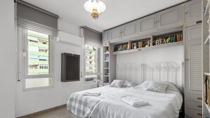 Une chambre à coucher avec un lit, une télévision, une bibliothèque et une fenêtre.