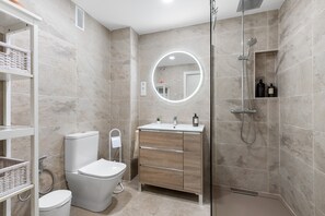 Un baño moderno con inodoro, lavamanos y ducha.