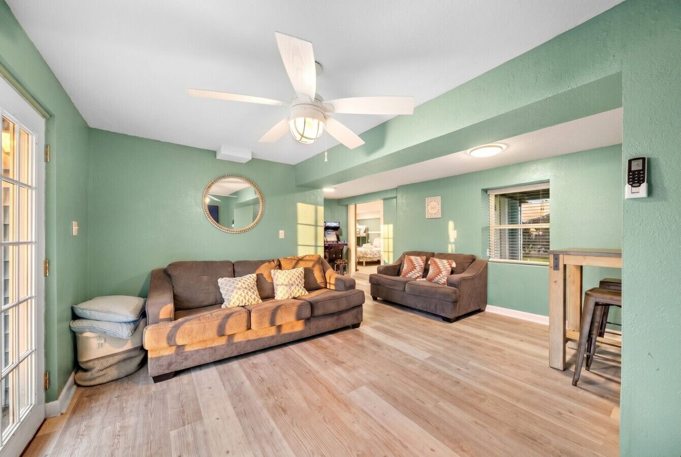 A spacious living room with two sofas, a ceiling fan, and a wooden floor.