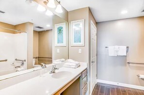 A modern bathroom with a large mirror, a sink, and a shower area. - Sterling Reef 405 (Panama City Beach)