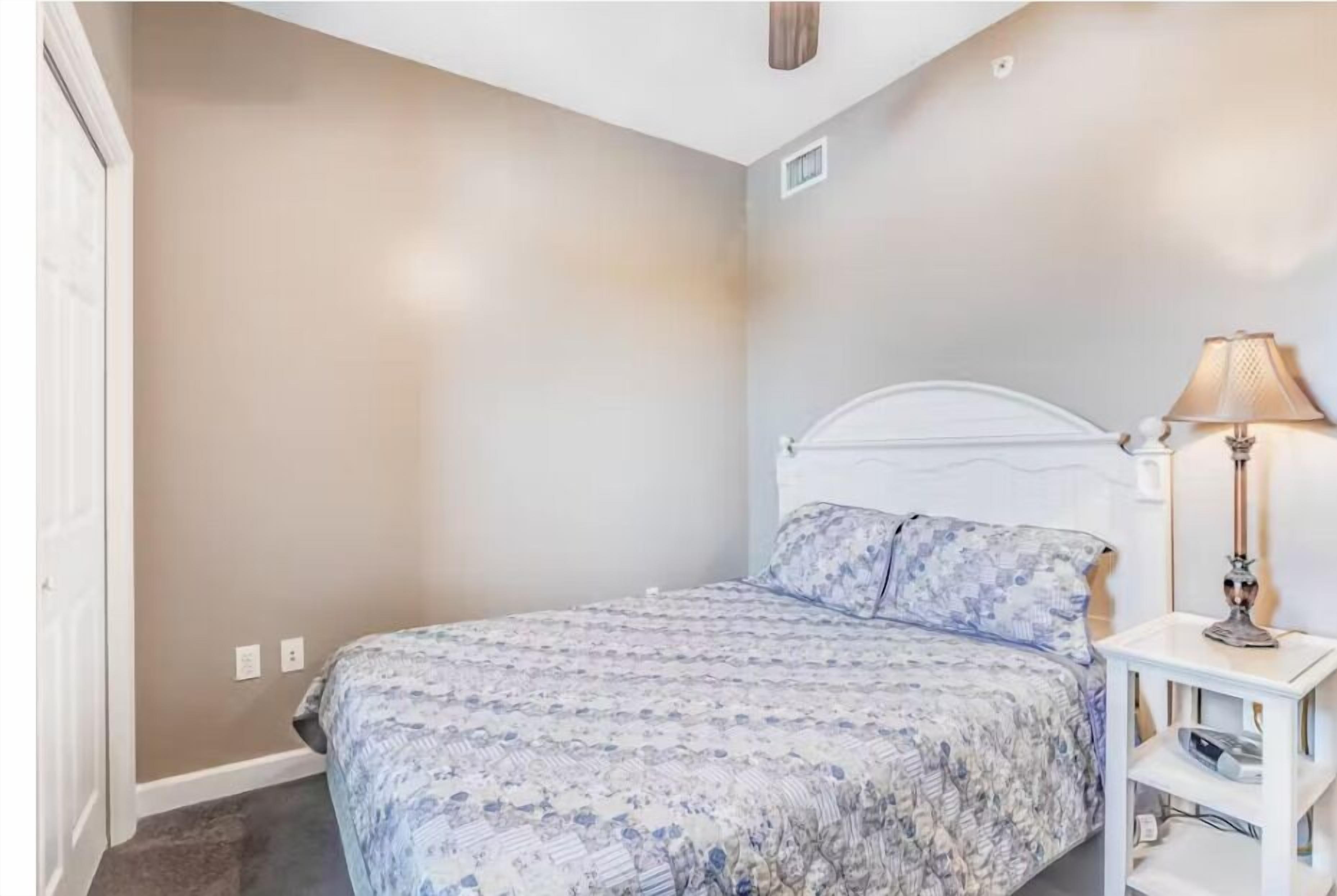 A bedroom with a bed, a nightstand, and a lamp.