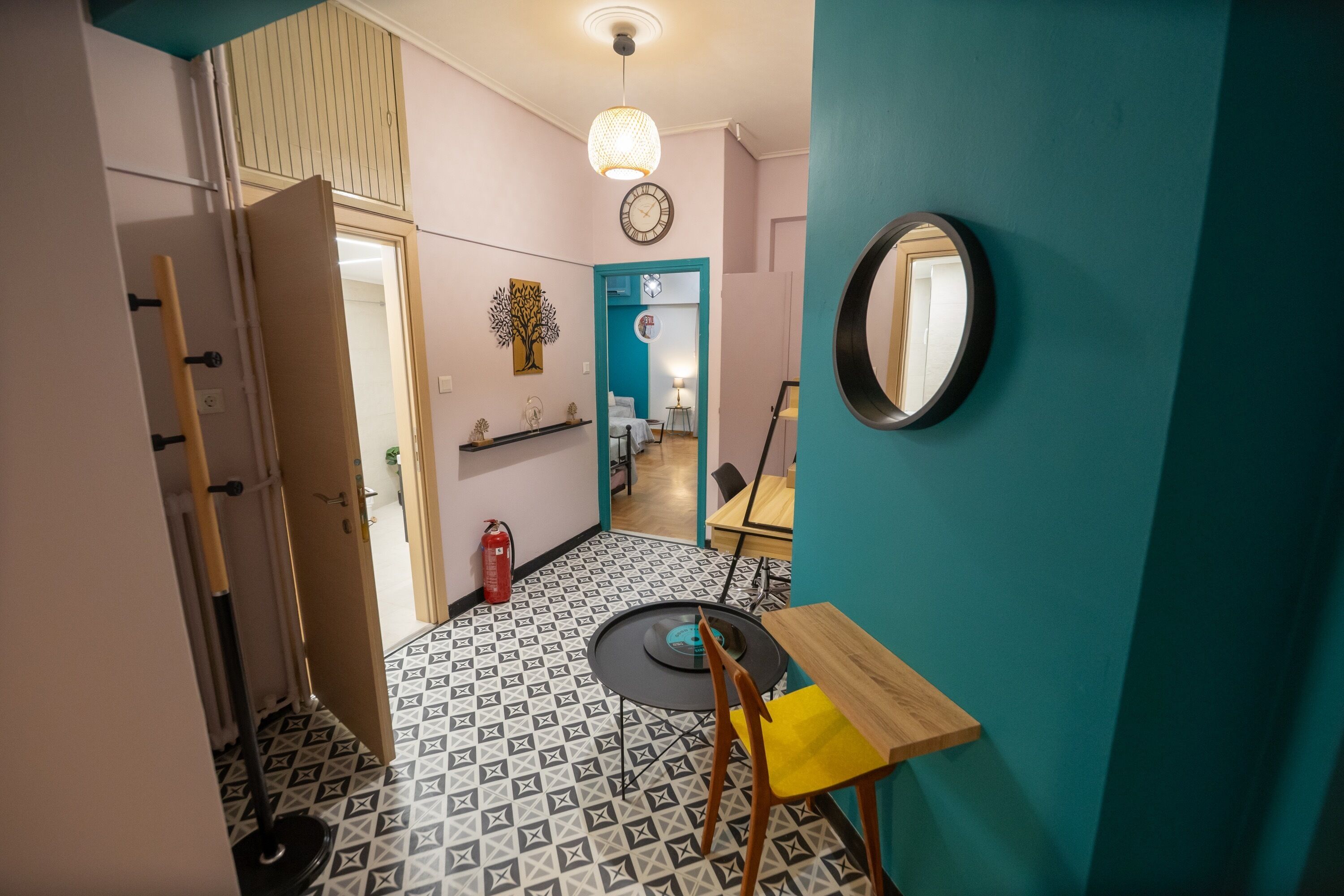 Een compacte kamer met een kamer met een patroon vloer, een ronde spiegel, een klein tafeltje en een stoel.