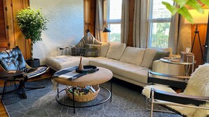 A cozy living room with a leather chair, a sofa, a coffee table, and a large potted plant. - Stay at adorable mill house in walkable Maynard. Small but well-designed spaces. (Maynard)