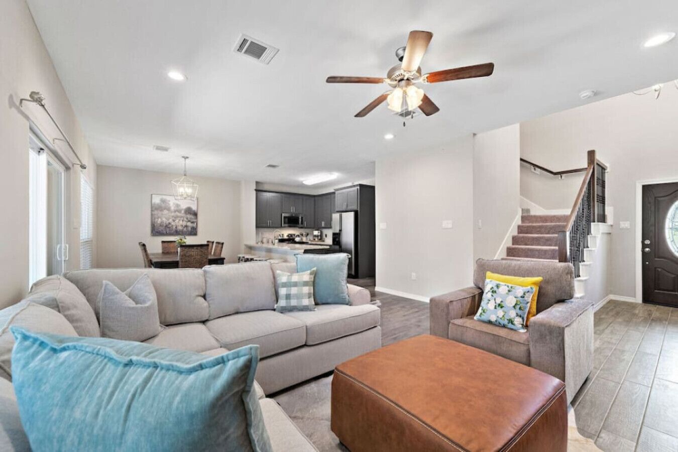 A spacious living room with a large sofa, a coffee table, and a ceiling fan.