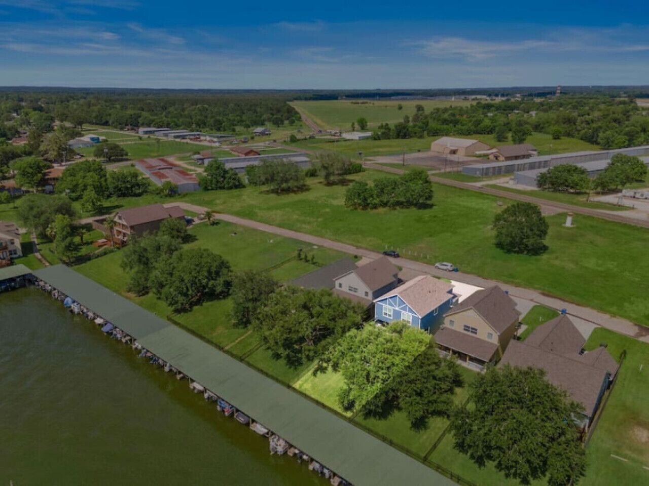 Vue aérienne d’un quartier résidentiel avec des maisons, un quai et une grande étendue d’eau.