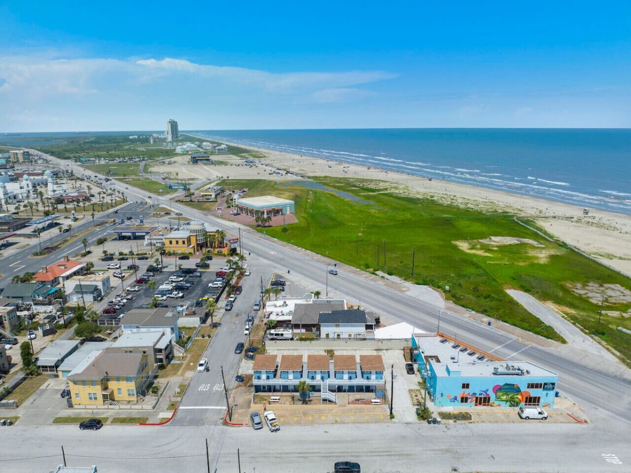 Vista aérea de un pueblo costero con playa, carreteras y edificios.