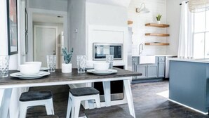 A modern kitchen with a wooden island, white cabinets, and a built-in microwave. - Historic Galveston Homes Near Everything (Galveston)