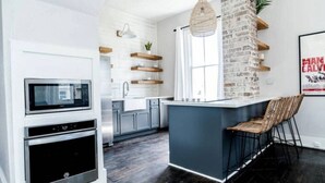 A modern kitchen with a central island, built-in oven, and a hanging light fixture. - Historic Galveston Homes Near Everything (Galveston)
