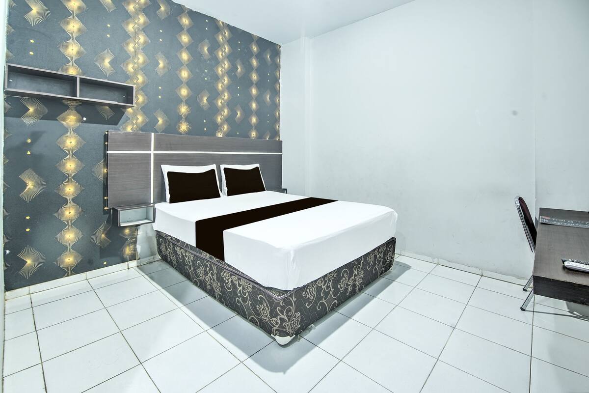 A modern bedroom with a bed, bedside tables, and a desk.
