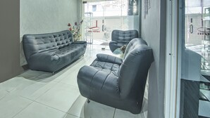 Un saló modern amb un sofà i butaques grises, una taula de centre de vidre i un vas decoratiu.