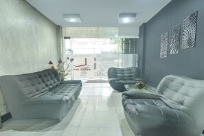 A modern interior with two leather sofas, a glass coffee table, and decorative wall panels. - Hotel O Makassar near Mall Panakukang formerly Hotel Lucky Inn Makassar (Makassar)