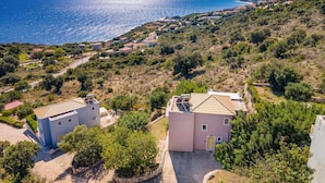 A coastal residential area with houses, a clear view of the sea, and a hilly landscape. - Villa Apollon by Villa Plus (Ionian Islands)