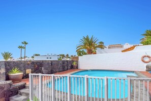 Une piscine sur le toit, avec un mur en pierre et des palmiers.