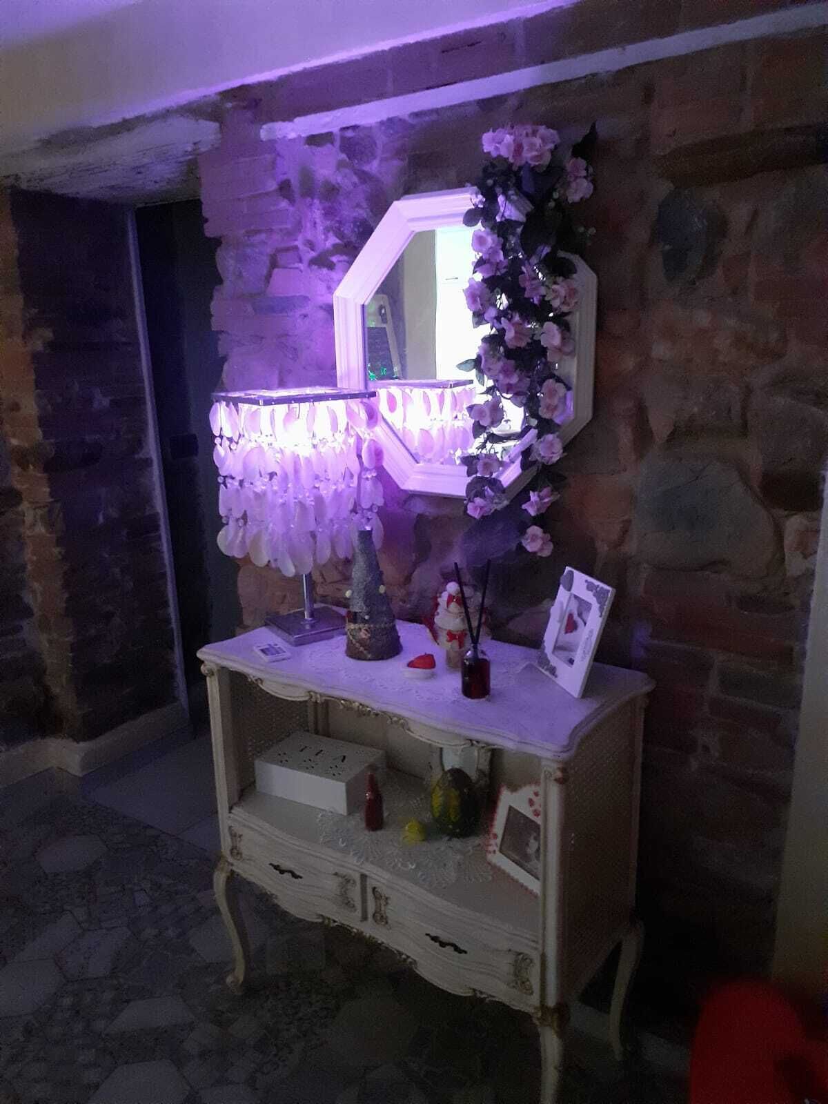 Un mobile da trucco in stile vintage con uno specchio, circondato da fiori decorativi e oggetti personali.