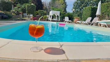 Una piscina con lettini da spiaggia e un gazebo bianco sullo sfondo.
