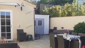 An outdoor patio area with stone flooring, wicker furniture, and a table with a patterned tablecloth. - THE HOUSE OF BAGGIORO (Capannori)