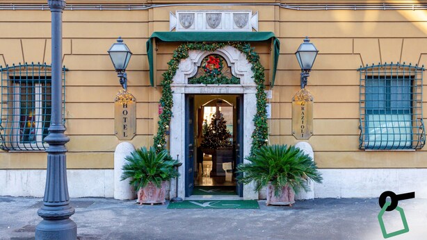 A hotel entrance with a Christmas tree, a green awning, and a sign that reads "HOTEL". - Hotiday Roma Borghese (Rome)