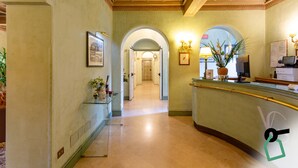 A hotel reception area with a curved counter, framed artwork, and a clock on the wall. - Hotiday Roma Borghese (Rome)