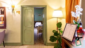 A hotel room with a green door, a table with a menu, a bottle of Aperol, and a potted orchid. - Hotiday Roma Borghese (Rome)