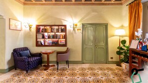 A room with a patterned floor, a bookshelf, two chairs, a door, and a wall-mounted lamp. - Hotiday Roma Borghese (Rome)