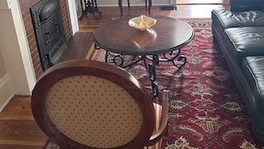 A living room with a fireplace, a television, a dining table with chairs, a sofa, and a patterned rug.
